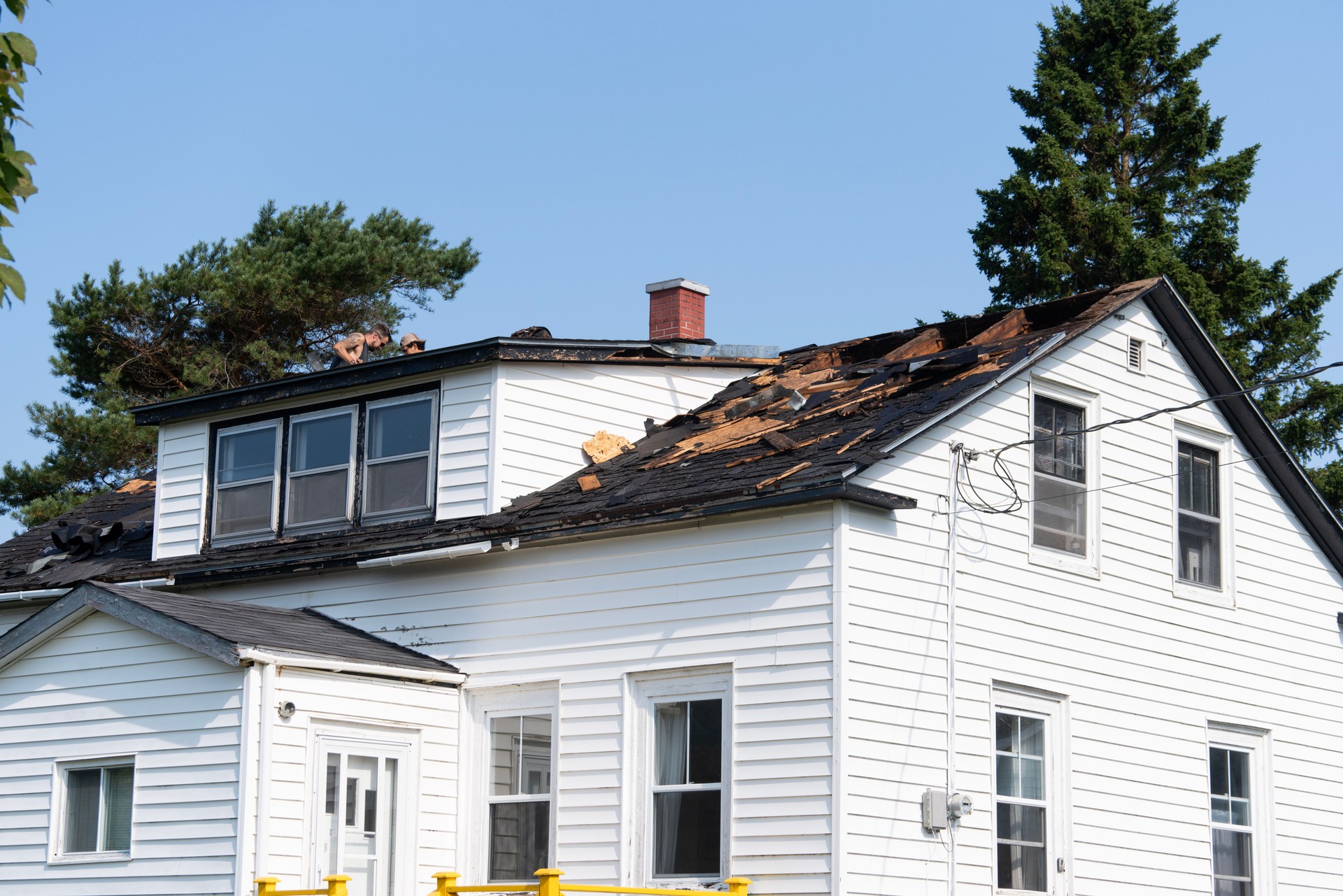 An old house being renovated.  Tradesmen are replacing the roof.