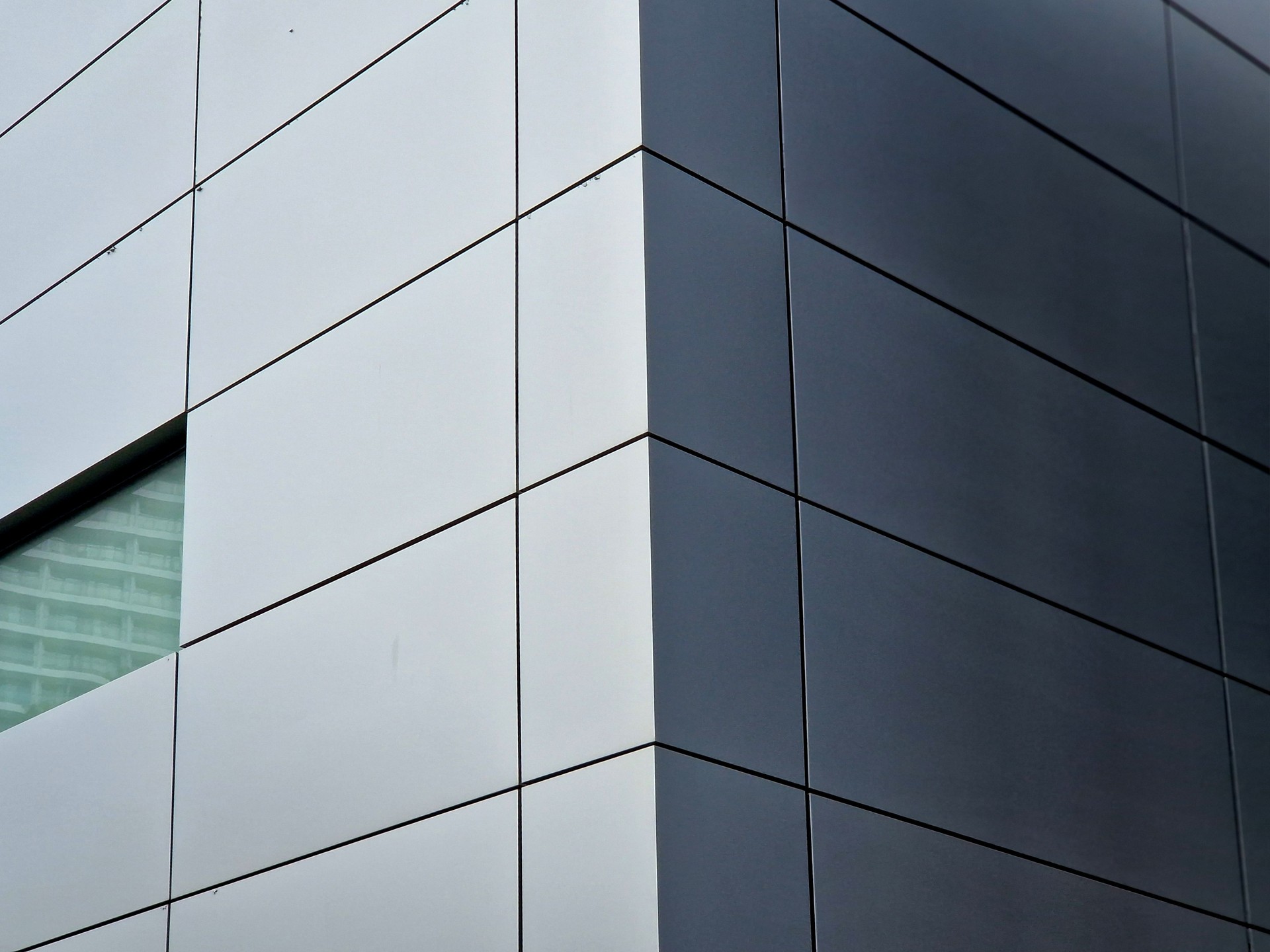 cladding of a building with a expanded metal lattice structure. galvanized gray nets protect the industrial building. Blue sky in contrast to a silver background, wall, corner, slanted, sheet metal